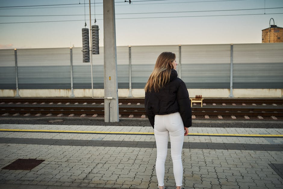 A woman stands at Leibnitz train station, Steiermark, Austria, waiting on a sunny day.