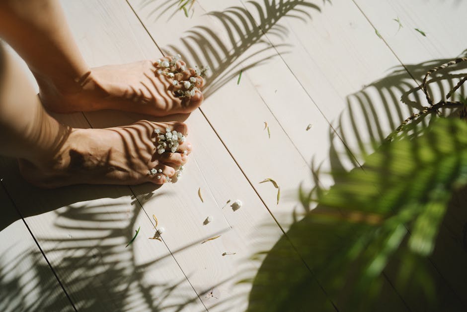 A tranquil scene of barefoot feet adorned with white flowers and natural shadows on wooden flooring.
