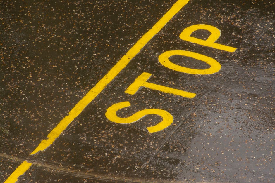 Rain-soaked road with a painted yellow STOP sign for traffic control.